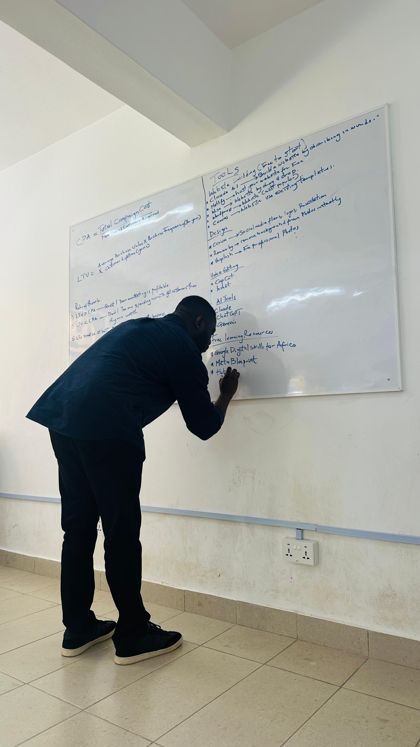 Daniel writing practical marketing tools on a classroom whiteboard