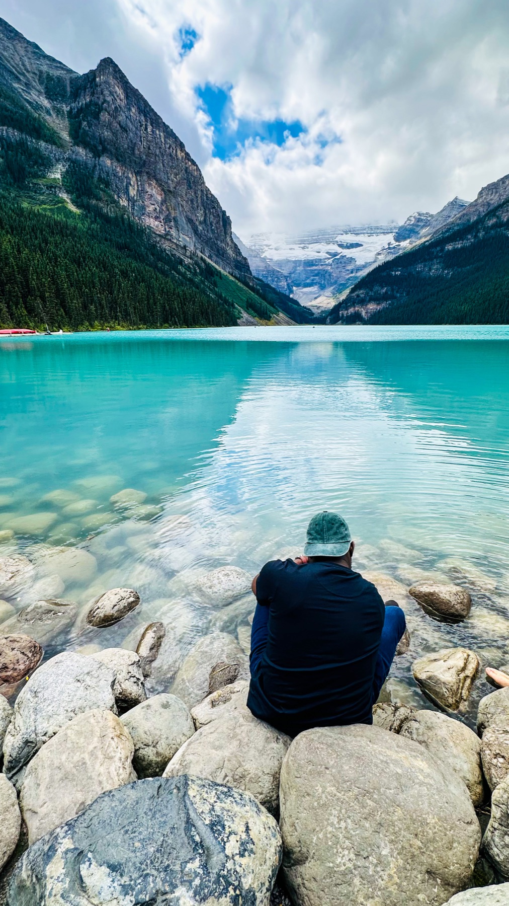 Daniel sitting beside the turquoise water and mountains at Lake Louise