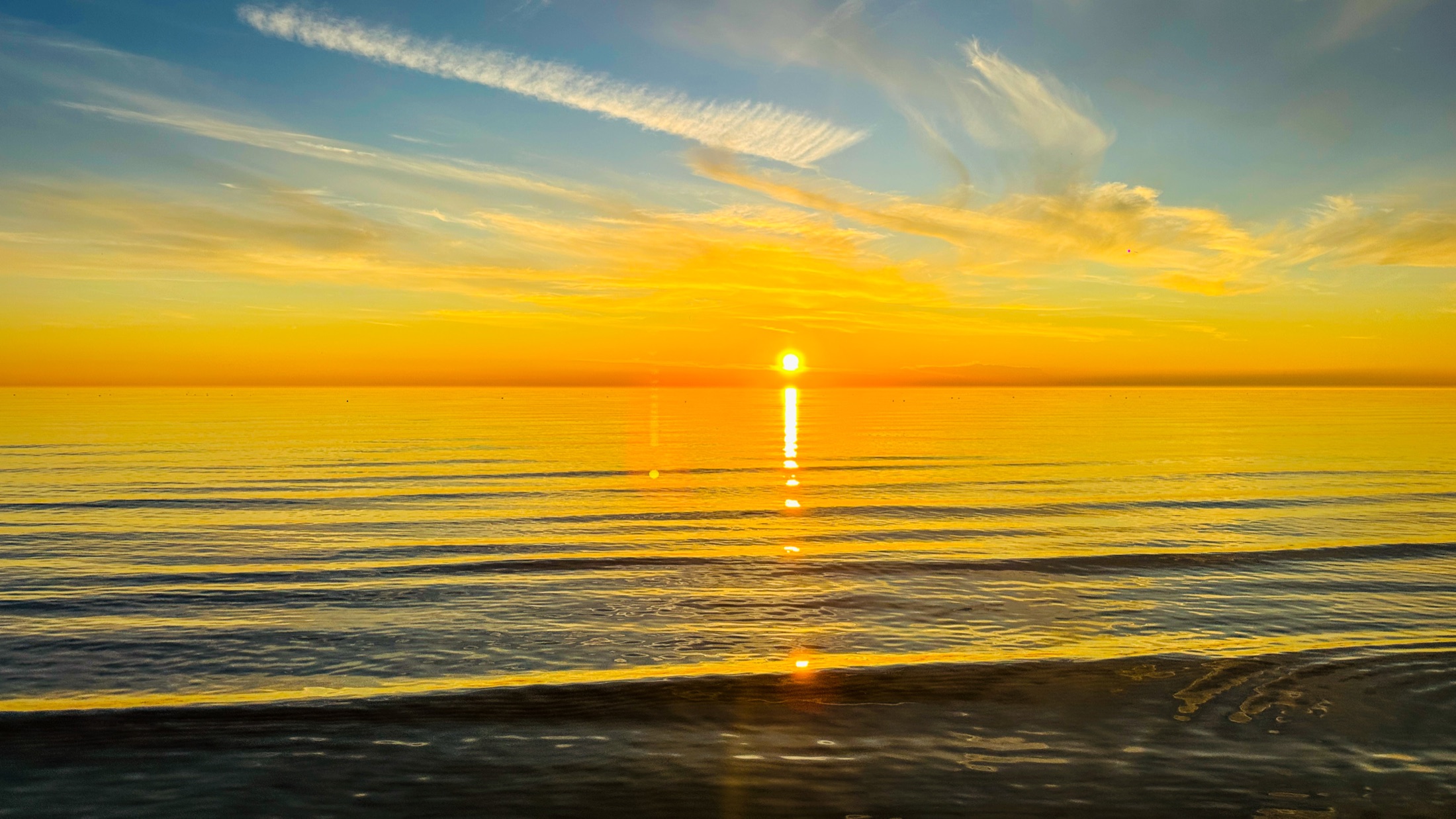A golden sunset reflected across calm water, photographed by Daniel